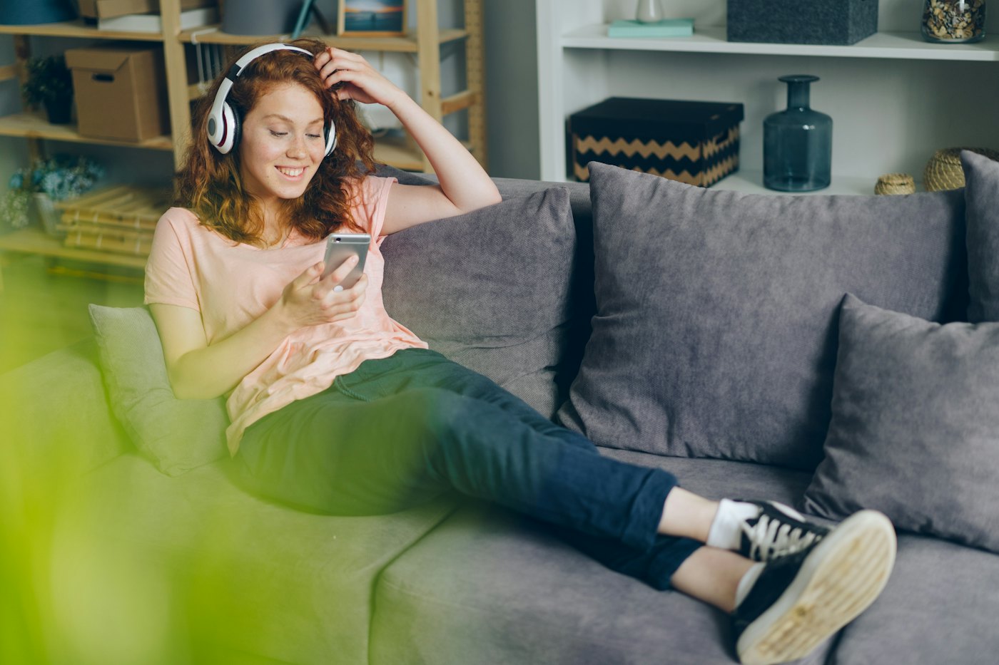 Chica en el sofá con auriculares y el móvil