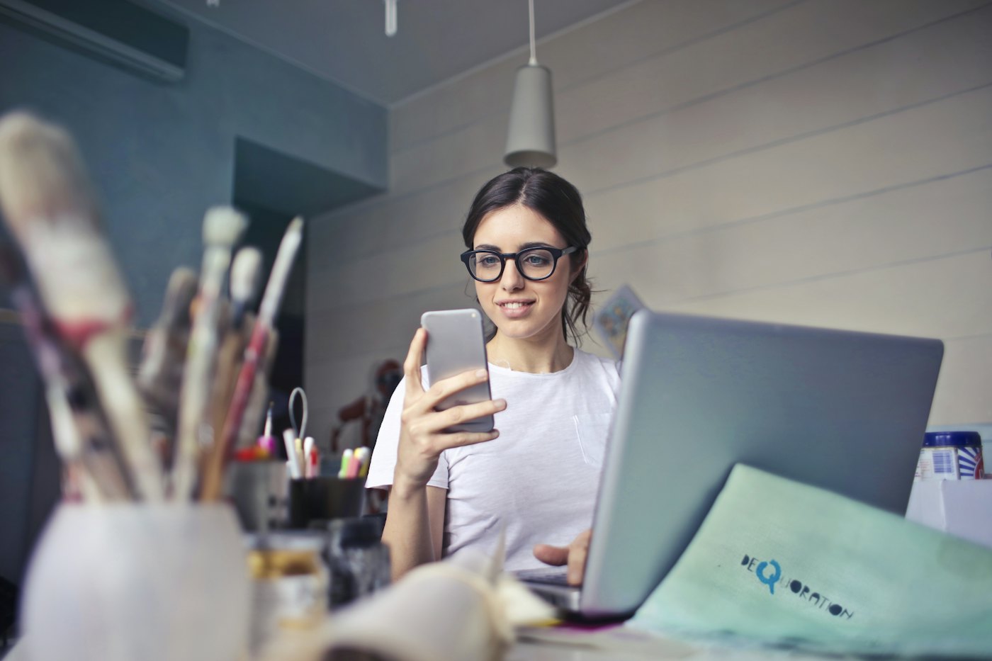 Mujer con gafas usando el móvil y el portátil