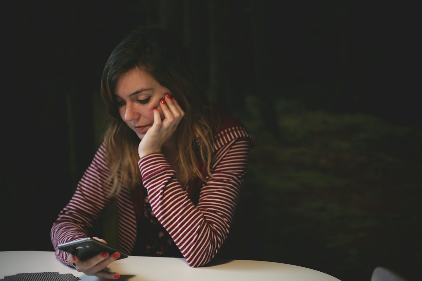 Mujer consultando el móvil en la mesa de casa